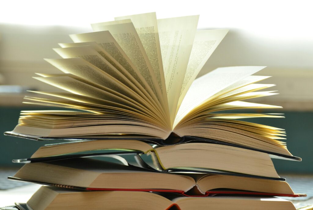 Alt text: A stack of books with one open at the top, showcasing its pages fanned out. The image represents knowledge and learning, relevant to Friday Health.