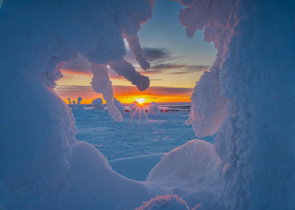 A stunning winter sunrise viewed through a natural ice formation, with the vibrant colors of the sky reflecting off the snow, symbolizing the beauty of Friday Health and wellness in nature.