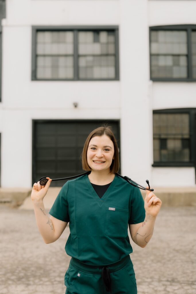 A smiling Kendra Tielemans professional wearing green scrubs and holding a stethoscope stands in front of a building. The words "Friday Health" are relevant to the imagery, emphasizing the connection to healthcare and well-being.