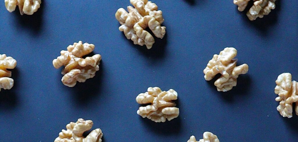 A flat lay of walnut halves arranged on a dark background, emphasizing the health benefits of walnuts in line with Friday Health.